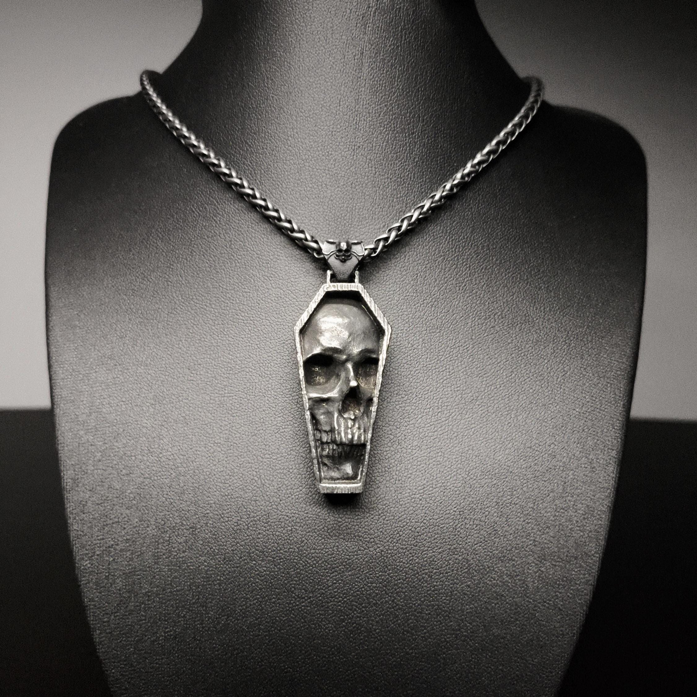 Skull-shaped pendant on a chain necklace displayed on a mannequin bust.