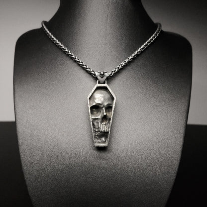 Skull-shaped pendant on a chain necklace displayed on a mannequin bust.