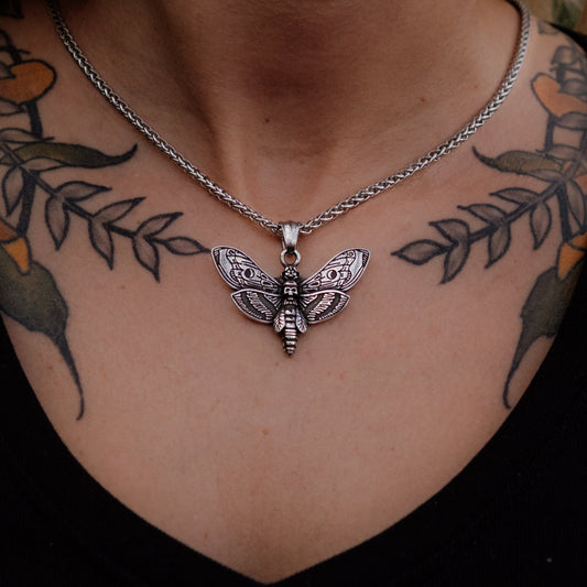 Silver butterfly pendant necklace on a person with tattoos