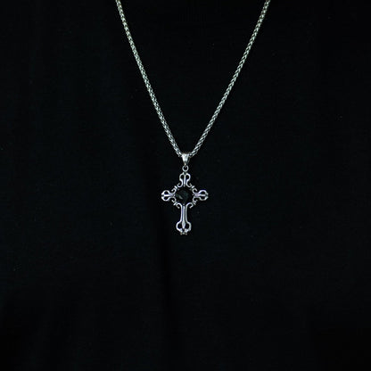 Person wearing a black shirt with a silver necklace featuring a cross pendant.