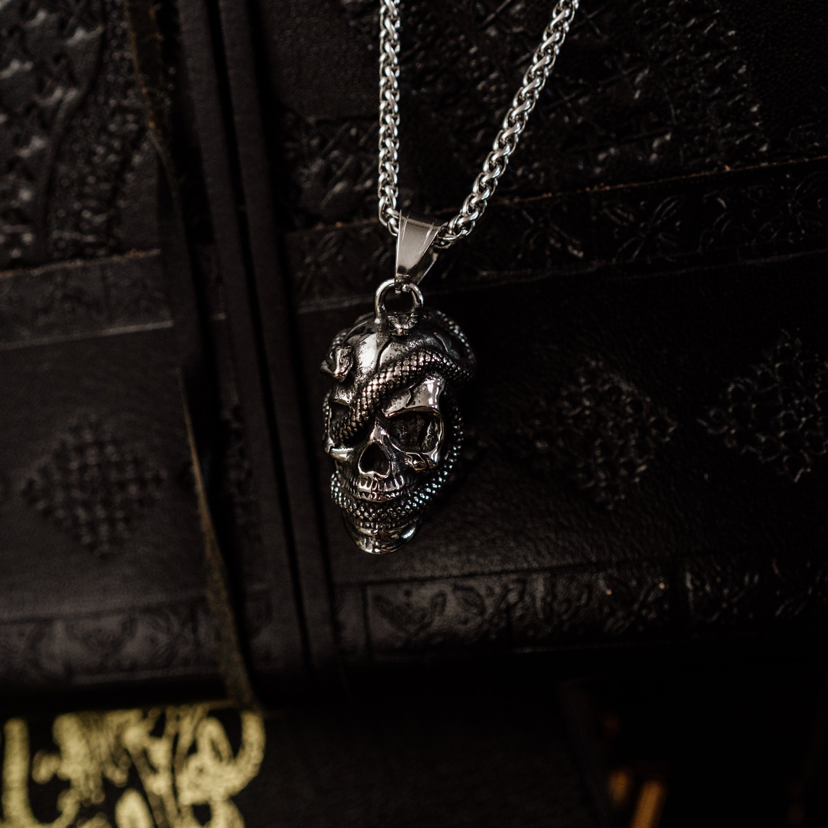 Silver skull pendant necklace on a dark textured surface