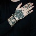 Person with tattoos on arm and hand wearing a black shirt