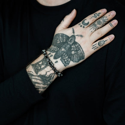 Person with tattoos on arm and hand wearing a black shirt