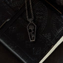 Black coffin-shaped pendant necklace on a black notebook