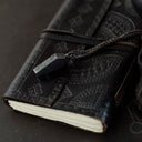 Black leather-bound notebook with chain and clasp on a dark surface