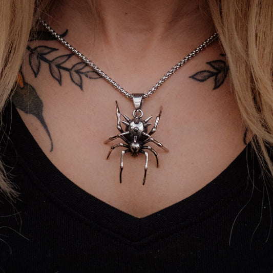 Spider necklace worn by a person with tattoos on their neck