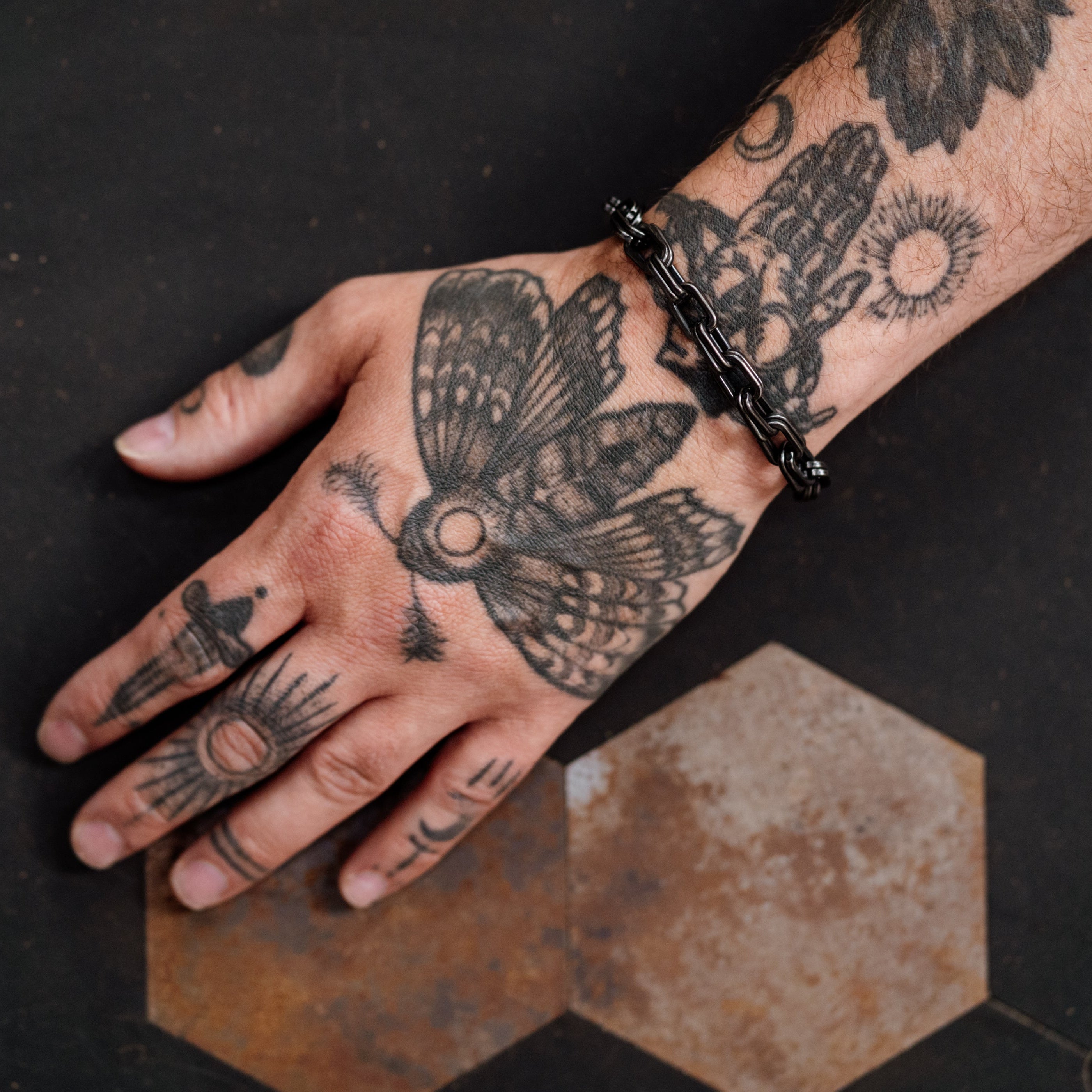 Hand with tattoos on a dark surface