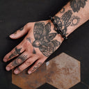 Hand with tattoos on a dark surface