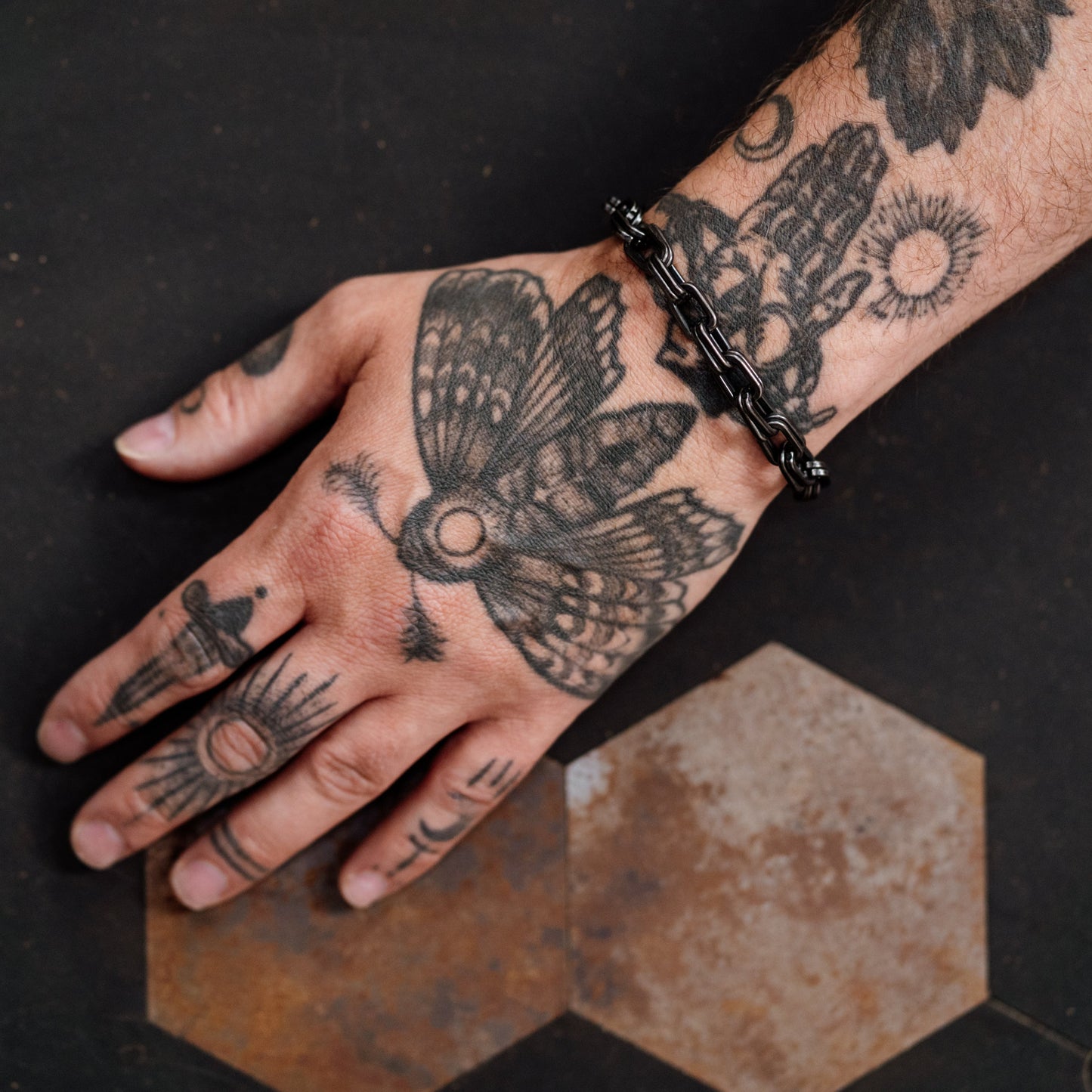 Hand with tattoos on a dark surface