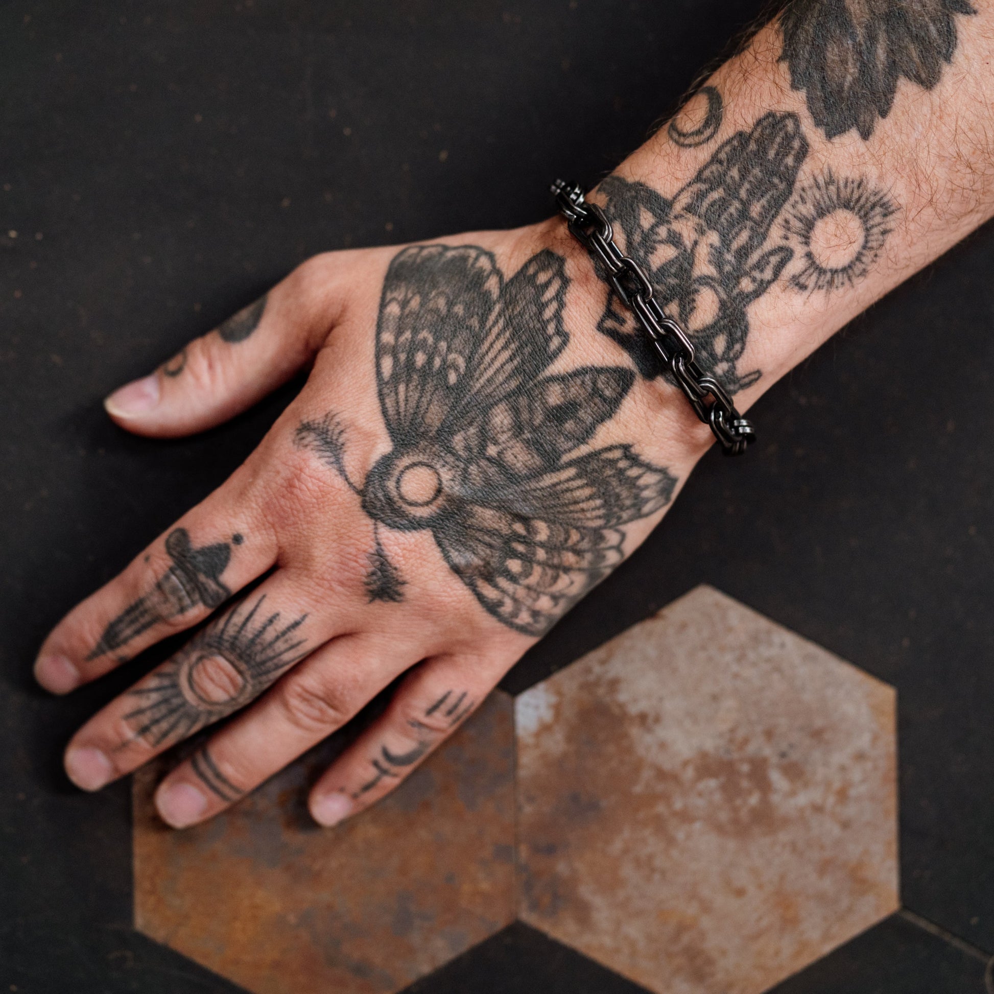 Hand with tattoos on a dark surface