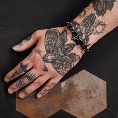 Hand with tattoos on a dark surface