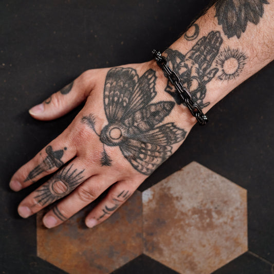 Hand with tattoos on a dark surface